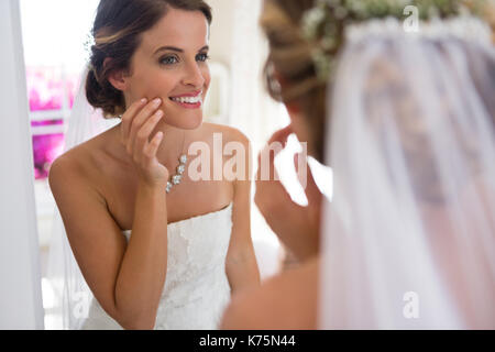 Beautiful bride looking into mirror while standing in fitting room Stock Photo