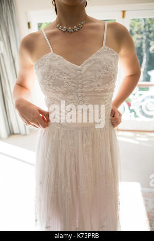 Midsection of young woman in wedding dress standing at home Stock Photo
