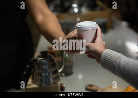 Mid section of waiter serving coffee to woman at counter in restaurant Stock Photo