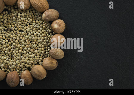 Overhead of white peppers surrounded with nutmegs Stock Photo