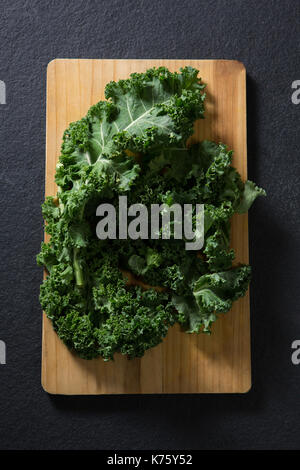 Overhead of mustard greens on chopping board Stock Photo