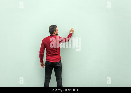 Young adult businessman painting on gray wall. Studio shot Stock Photo