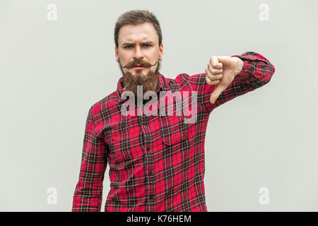 Handsome bearded man showing thumbs down sign to dislike, isolated on gray background Stock Photo
