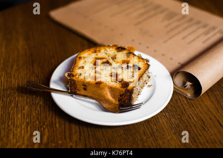 Sponge cake with nuts, raisins and dry fruit placed on the wooden table. The side view. Stock Photo