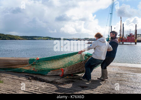 Killybegs, County Donegal, Ireland.  Fishermen in Ireland's premier fishing port take advantage of some sunshine to dry out fishing nets on the quaysi Stock Photo