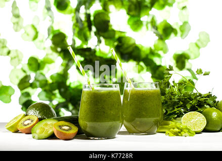 Freshly blended green smoothie in glasses with straws on green leaves background Stock Photo