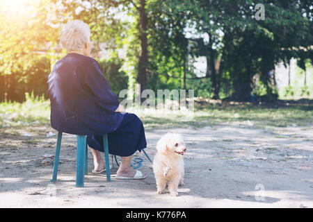 Old woman raising dogs in backyard Stock Photo