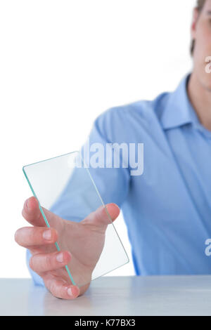 Cropped image of businessman showing glass interface at table against white background Stock Photo