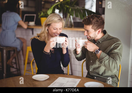 Smiling young couple drinking coffee while sitting at table in cafe Stock Photo