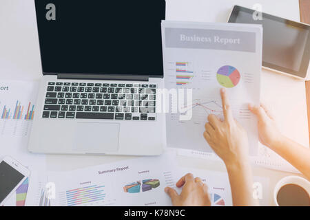 Businessman checking graph with a laptop,coffee phone  on the table when the morning light. Stock Photo