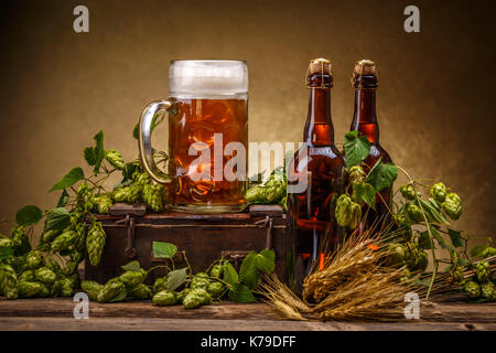 Glass and bottles of beer with green hops decoration on wooden table Stock Photo