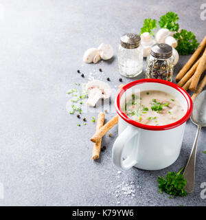 Delicious homemade mushrooms champignons soup with parsley in enamel mug. Healthy food concept with copy space. Stock Photo