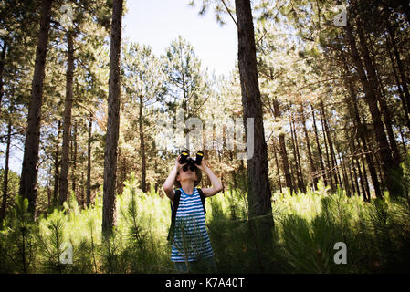 Boy looking through binoculars in woods Stock Photo