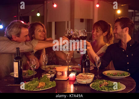 Friends clinking wine glasses at dinner party Stock Photo