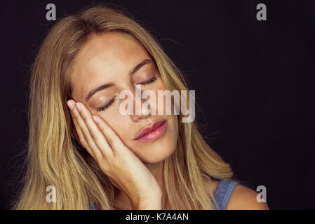 Young woman resting cheek on hand, eyes closed, portrait Stock Photo