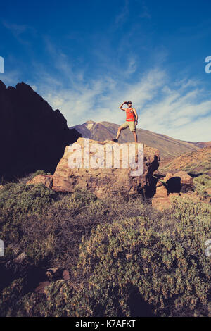 Man celebrating beautiful inspiring view in mountains. Hiker or climber looking at inspirational landscape on rocky trail on Tenerife, Canary Islands. Stock Photo