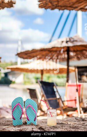 Slippers with a drink on the sand, water view, beach, summer, relaxation and enjoyment Stock Photo