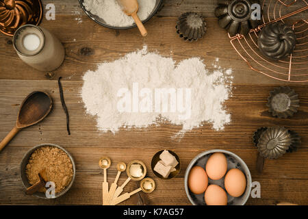 Flatlay collection of tools and ingredients for home baking on a dark wooden table with flour copyspace in the center shot from above Stock Photo