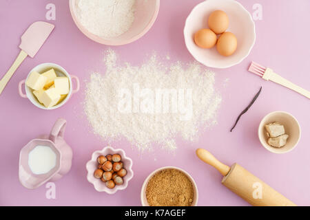 Flatlay collection of tools and ingredients for home baking with Flour copyspace in the center on pink background shot from above Stock Photo