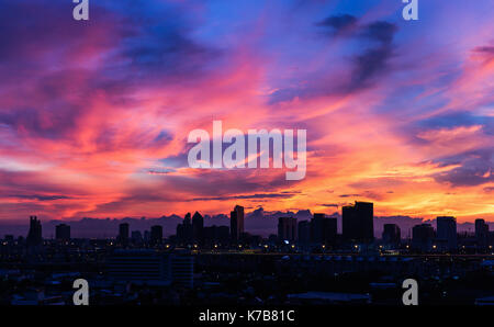 Dark city covered by dramatic colorful morning sky with moving clouds before sunrise after storm at night Stock Photo