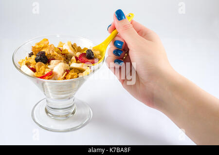 Female hand picking up granola from the bowl with spoon. Stock Photo