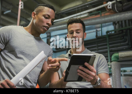 Men working in industrial setting using digital tablet Stock Photo