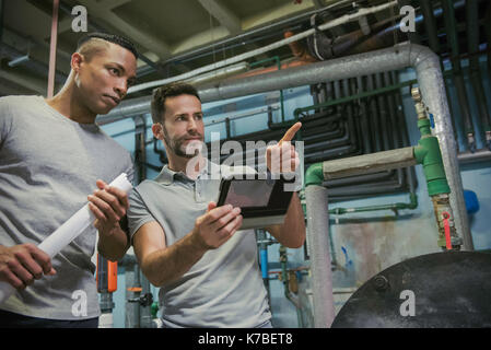 Men working in industrial setting using digital tablet Stock Photo
