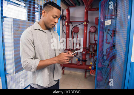 Man using mobile phone near fire protection sprinkler system Stock Photo