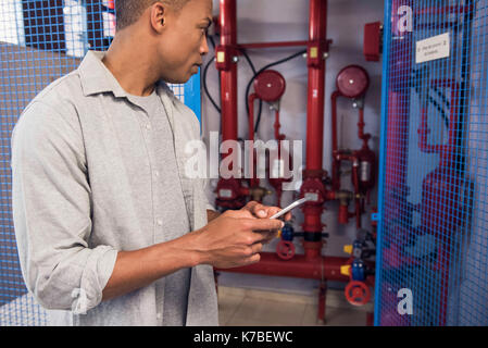 Man using mobile phone near fire protection sprinkler system Stock Photo