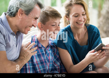 Family looking at smartphone together Stock Photo