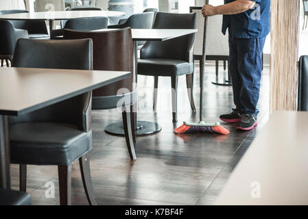 Man sweeping restaurant floor Stock Photo