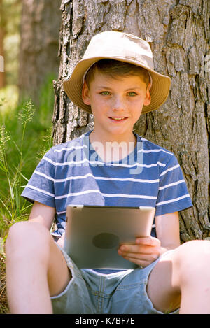 Boy using digital tablet in woods Stock Photo