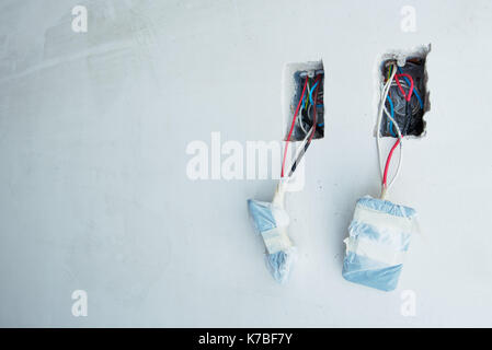 Electrical wires dangling from unfinished outlets in wall Stock Photo