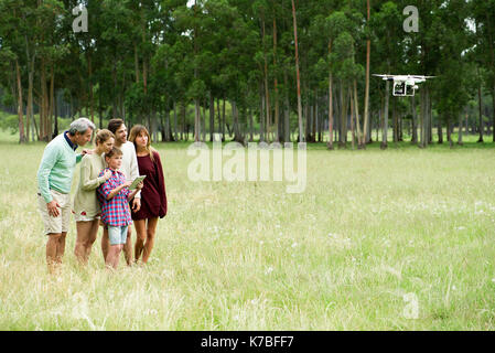 Boy operating remote control drone while parents and grandparents watch Stock Photo