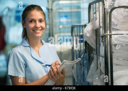 Woman checking cart of laundered bath towels Stock Photo