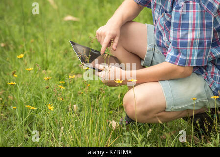 Boy using digital tablet in meadow, cropped Stock Photo