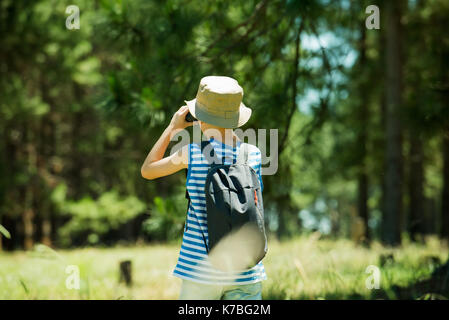 Boy looking through binoculars in woods Stock Photo