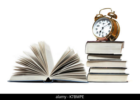 Alarm clock standing on stack of books near open book Stock Photo