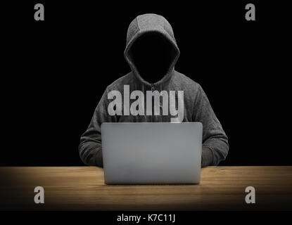 hooded man with empty face working with notebook isolated on black Stock Photo