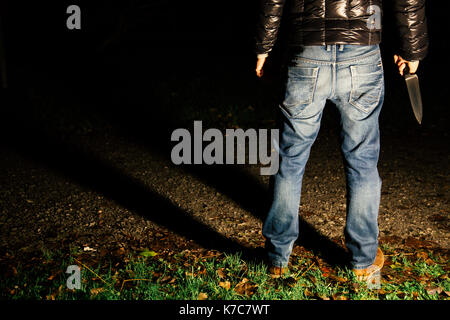 Criminal holding a knife ready to commit an aggression at night Stock Photo