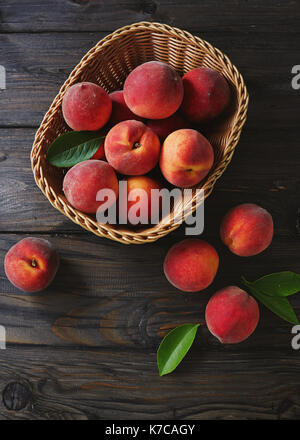 Basket of fresh peaches on a wooden table Stock Photo
