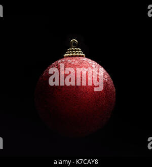 Red color sparkling christmas ball isolated against black background. Gradient light ambiance Stock Photo