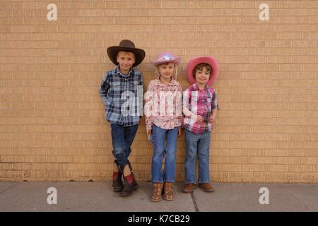 Three children dressed up as cowboys Stock Photo