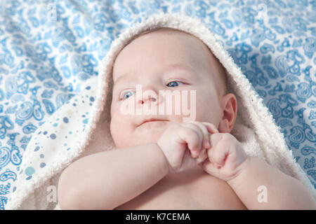 Cute three month baby wrapped bath towel after bath in bed at home Stock Photo