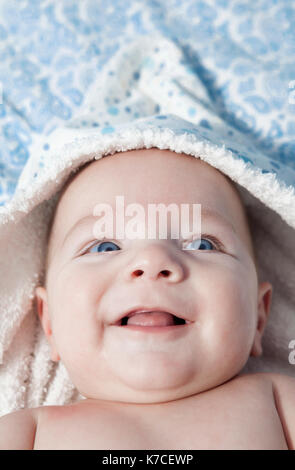 Cute three month baby wrapped bath towel after bath in bed at home Stock Photo