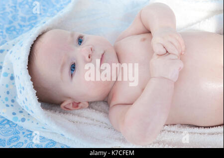 Cute three month baby wrapped bath towel after bath in bed at home Stock Photo