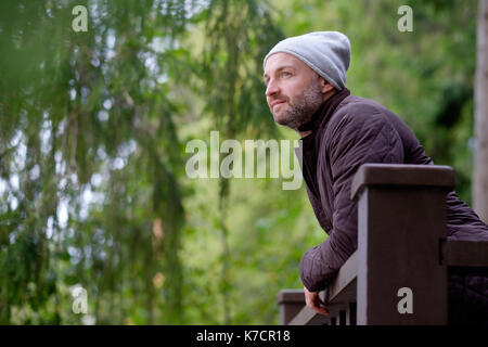 handsome mature man smiling in warm hat and jacket looking aside Stock Photo