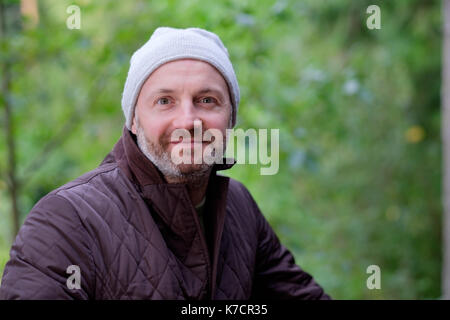 handsome mature man smiling in warm hat and jacket looking at camera Stock Photo