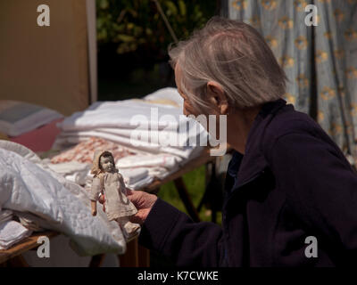 At Firle Vintage Fair in Sussex, an old woman studies a small doll Stock Photo
