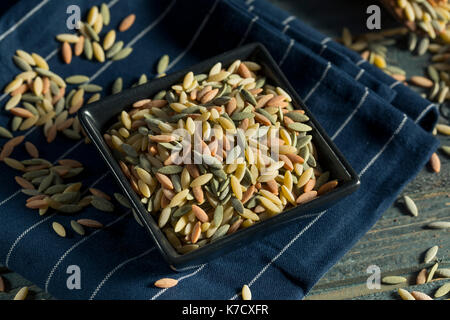 Dry Organic Tricolor Orzo Pasta in a Bowl Stock Photo